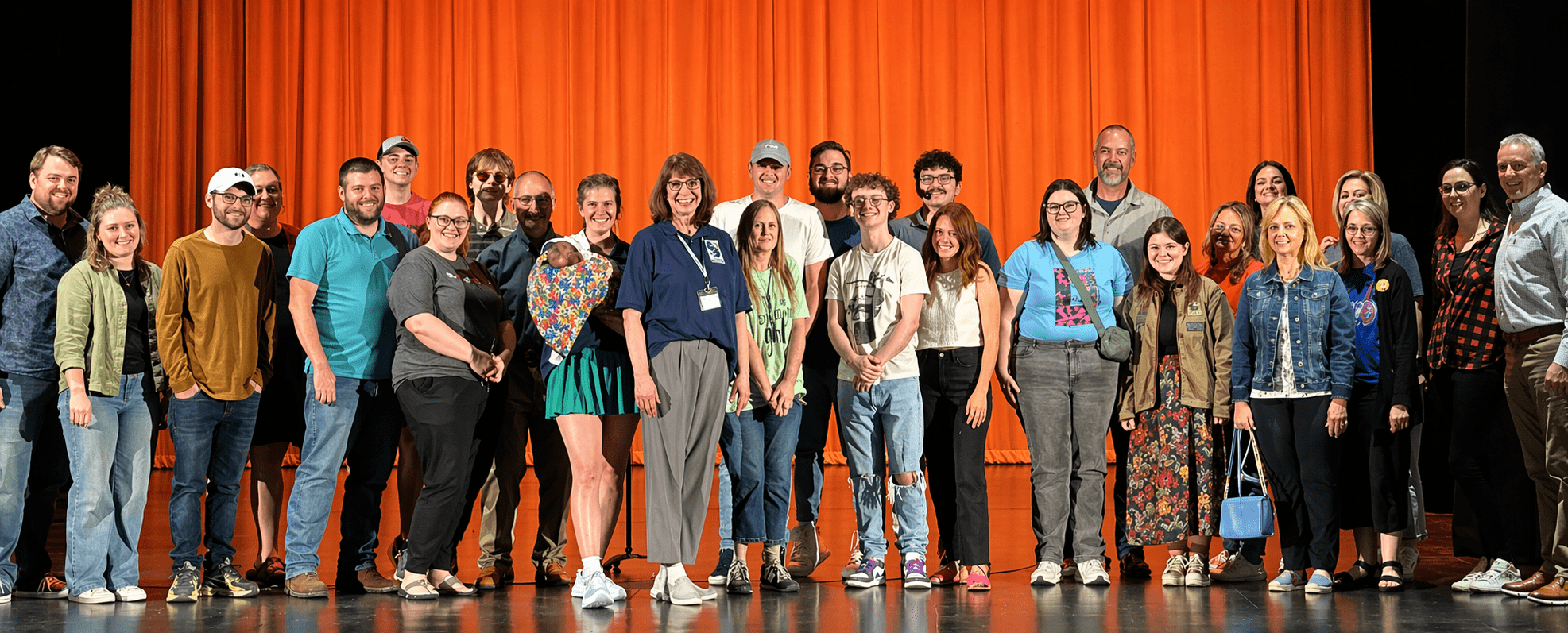 Diverse group posing in front of curtain.