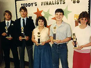 Five people holding trophies, smiling