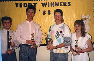 Four people holding trophies, smiling