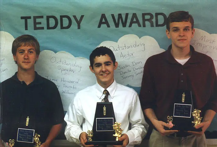 Three young men holding award trophies