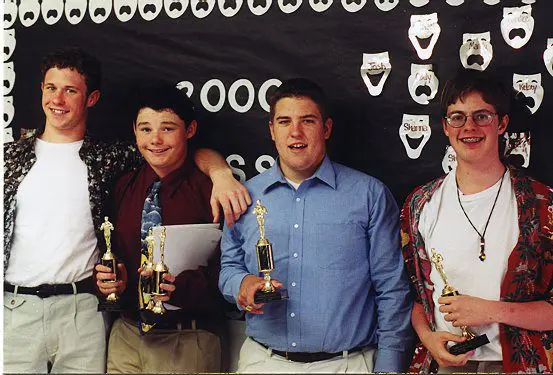 Smiling individuals posing with trophies