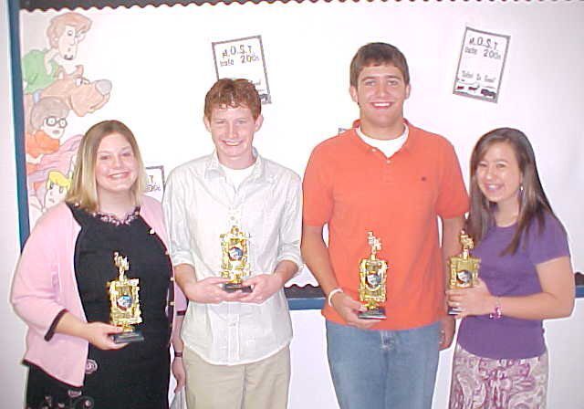 Four students proudly displaying trophies