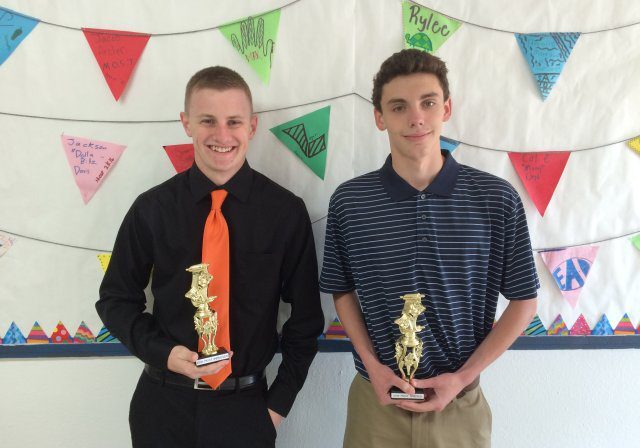 Two young men holding golden trophies