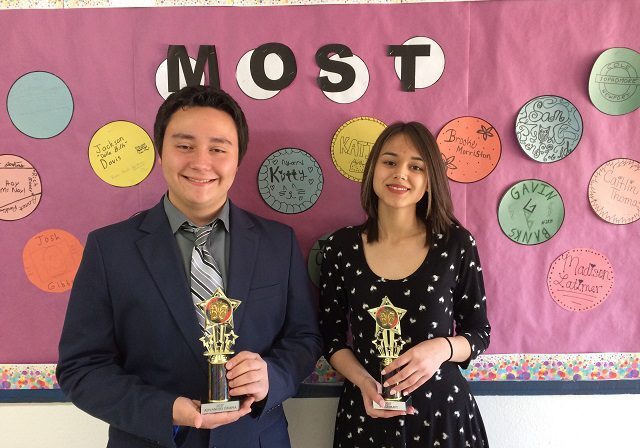 Two people holding trophies, smiling