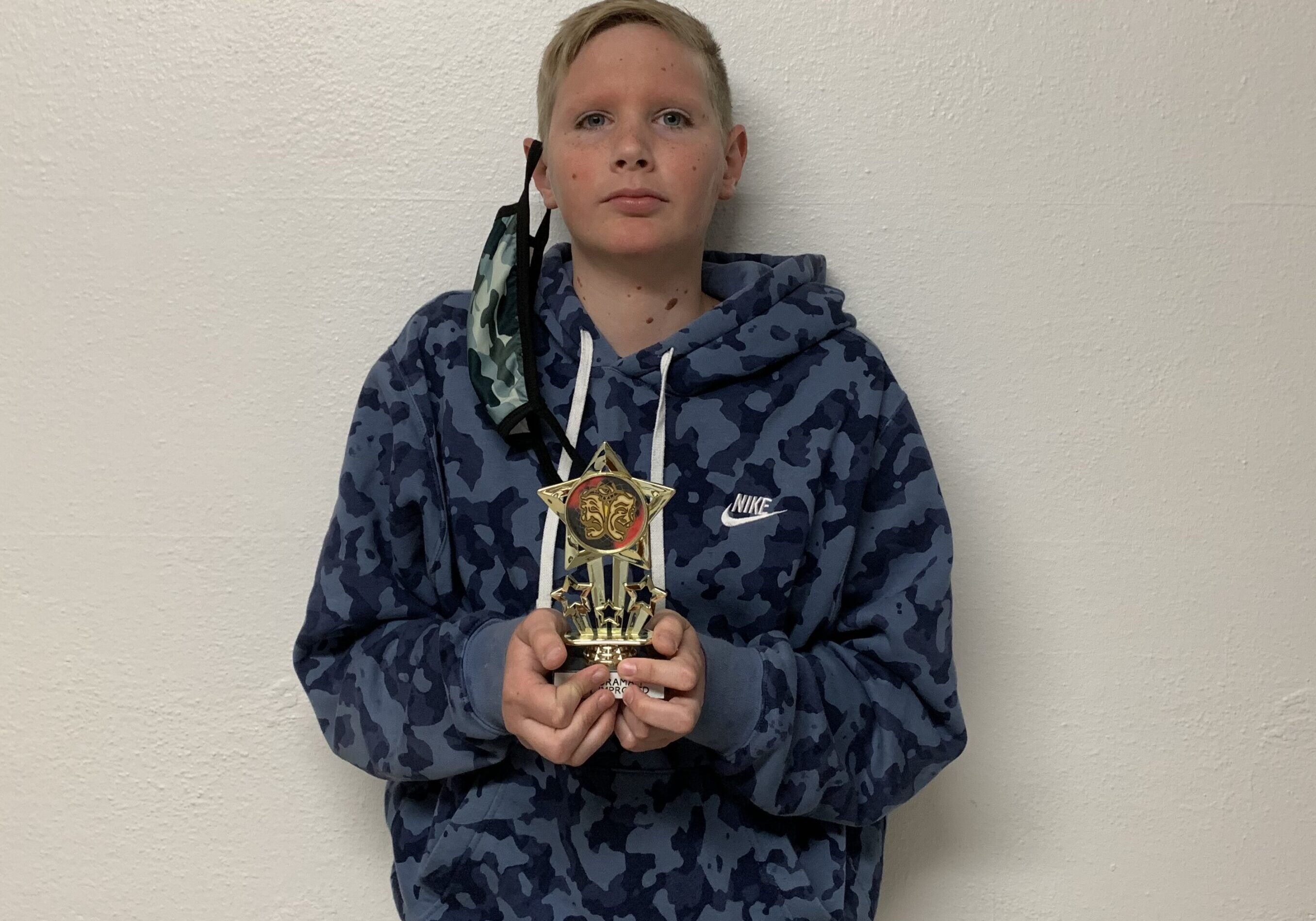 Young person proudly displaying a trophy.
