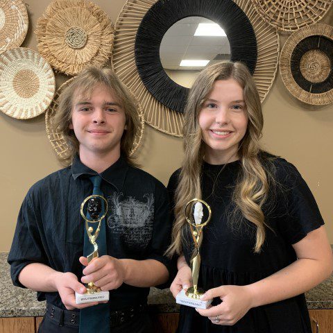 Two people holding awards, smiling